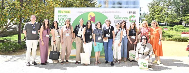 Foto de familia del Foro Vivir con C con un panel photocall detrás en un día soleado