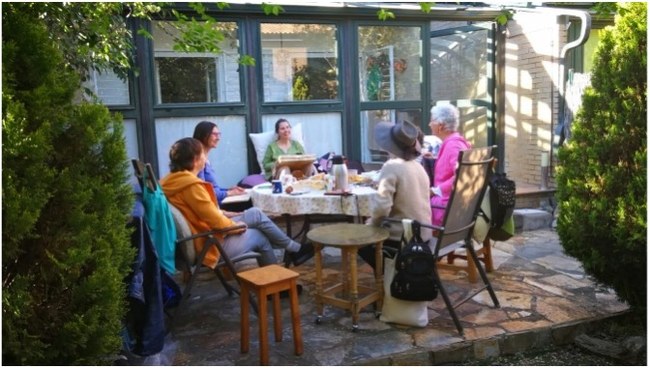 Un grupo de personas sentadas alrededor de una mesa en un patio exterior