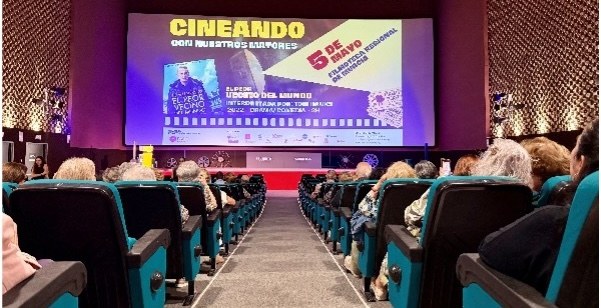 Una sala de cine llena, al fondo en la pantalla pone Cineando, imagen de proyecto finalista