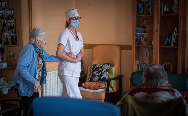 Persona mayor en una residencia acompañada de una profesional cuidadora