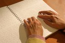 Las manos de una persona ciega leen un libro en braille
