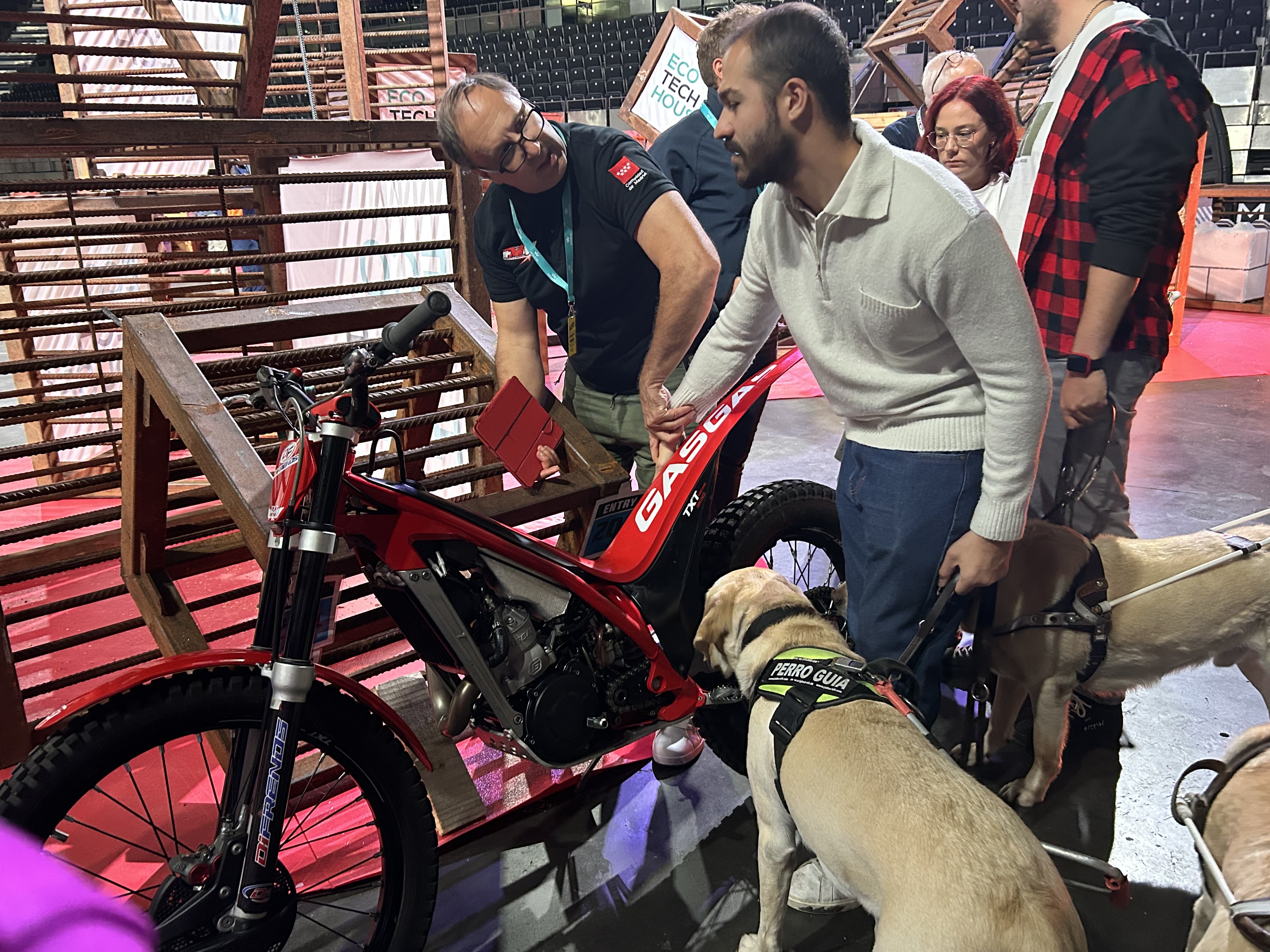 Javier Álvaro, uno de los asistentes, con su perro guía, tocando una de las motos de XTrial en la pista