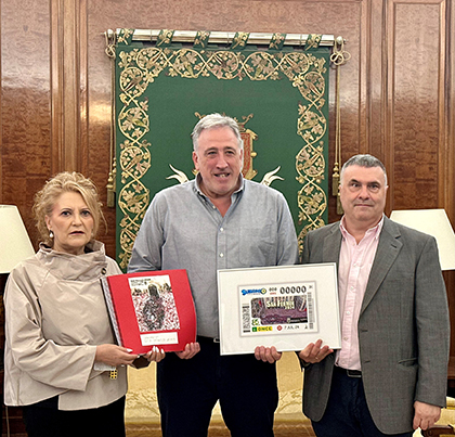 Pilar Herrero, Joseba Asiron Sáez y Valentín Fortún, con una lámina enmarcada del cupón y el programa de fiestas en braille