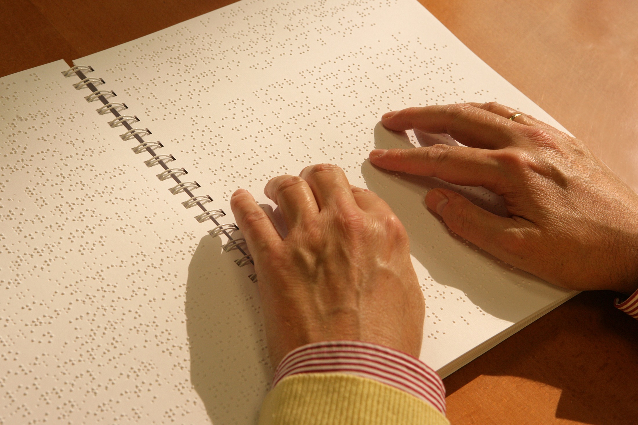 Manos de una persona ciega leyendo un libro en braille