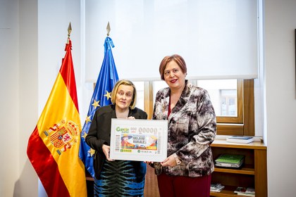 Imelda Fernández y María Begoña García sostienen una lámina enmarcada con este cupón