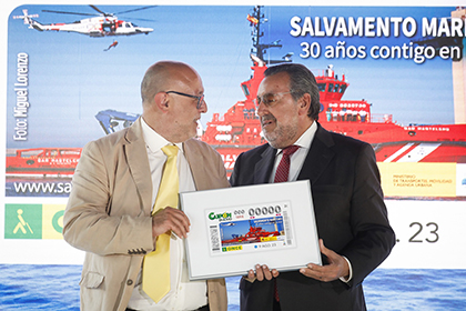 José Luis García Lena, a la izquierda, y Miguel Carballeda, sostienen un lámina enmarcada con el cupón dedicado al 30 aniversario de Salvamento Marítimo