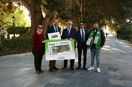 Fotografía de familia con la imagen del cupón junto al Ficus del Jardín Floridablanca