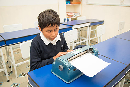 Estudiante ciego con máquina Perkins