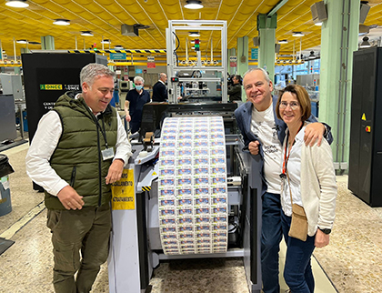 El equipo de Emprende, en la imprenta del cupón, junto a una bobina con los cupones dedicados al programa