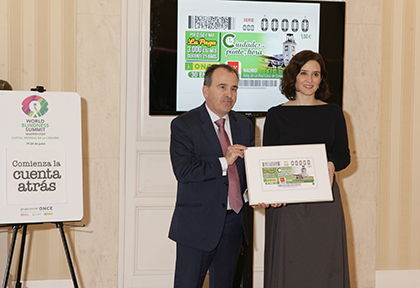 Isabel Díaz Ayuso y Luis Natalio Royo con una copia enmarcada del cupón dedicado al Reloj de la Puerta del Sol