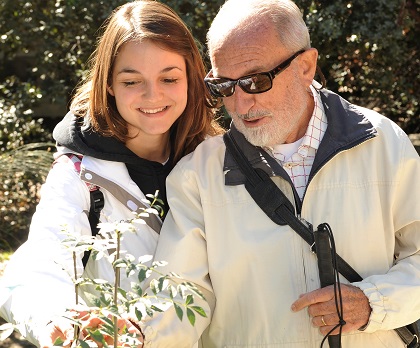 Voluntaria de la ONCE, junto a una persona ciega en un jardín de los sentidos