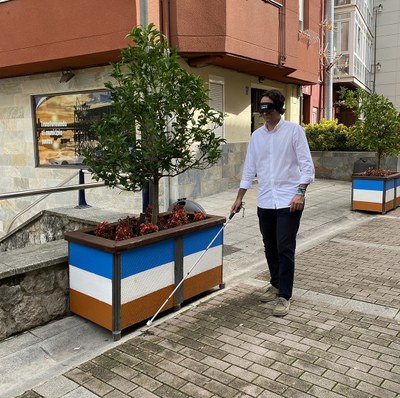 Javier Fernández, alcalde de Astillero, con antifaz y bastón blanco por las calles de la localidad