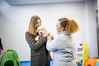 La Infanta Sofía sostiene un cachorro de futuro perro guía, junto a una de las instructoras de la FOPG