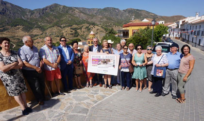 Autoridades y vecinos de Carratraca posan junto a la imagen del cupón delante del paisaje rural