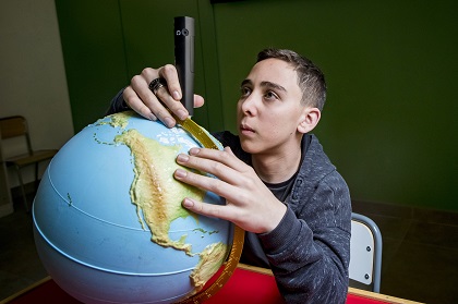 Alumno ciego con una bola del mundo adaptada en relieve