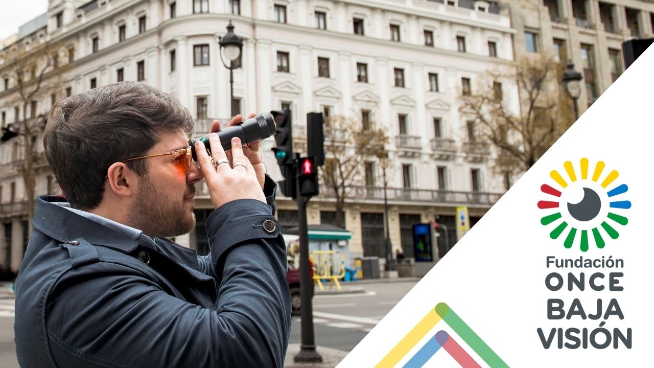 Un chico baja visión usando un telescopio en la calle