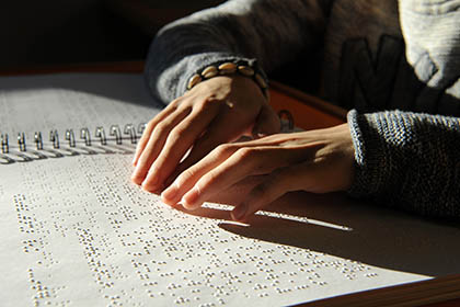 Imagen de unas manos leyendo un libro en braille