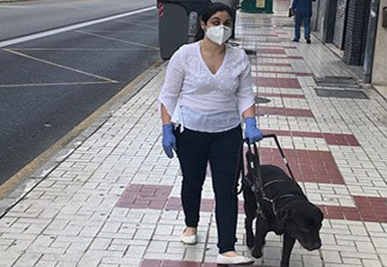 Una mujer ciega circula con su perro guía durante el estado de alarma dotada con mascarilla