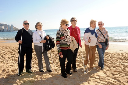 Grupo de personas mayores paseando por la playa