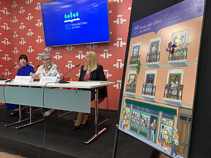 En primer plano, el cartel en relieve de la Feria del Libro de Madrid, que han presentado Carmen Bayari, Eva Orúe y María Simavilla