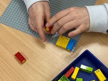 manos de un niño ciego con las piezas de LEGO Braille