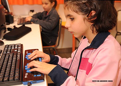 Una niña ciega utilizando el ordenador con línea braille en el aula