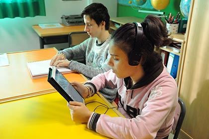 Un chico ciego lee un libro en braille junto a una compañera que lee en formato sonoroen una tablet