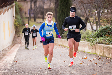Una atleta guía a otro en la Carrera de la Ilusión