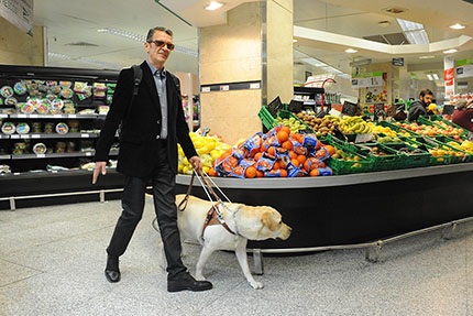 Persona ciega junto a perro guía en el supermercado