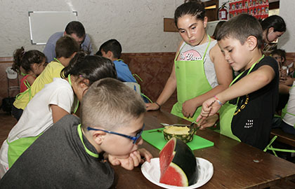 Varios chavales preparan sus recetas durante el campamento de verano