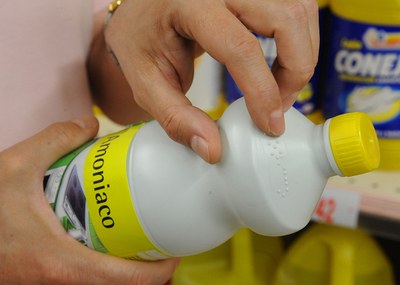 Una mano leyendo el braille de una botella de amoniaco Una mano leyendo el braille de una botella de amoniaco